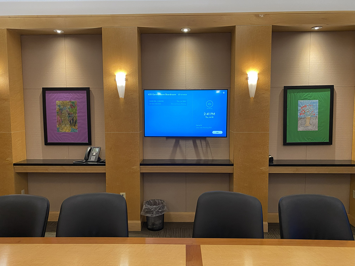 Digital display in Merakey conference room with art on either side