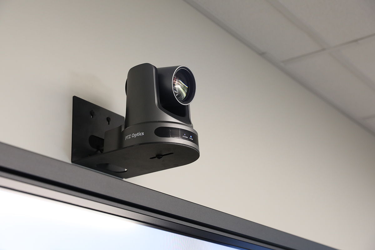 Wall-mounted PTZOptics camera above digital display